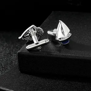 Macro shot of silver sailboat cufflinks with white enamel on a black jewelry box
