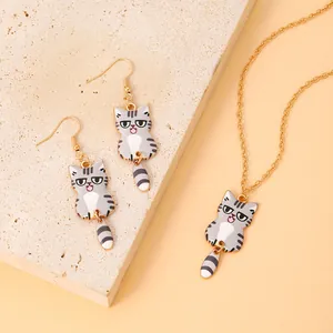 Detail of gray cartoon cat earrings and necklace set with movable tails and gold chain