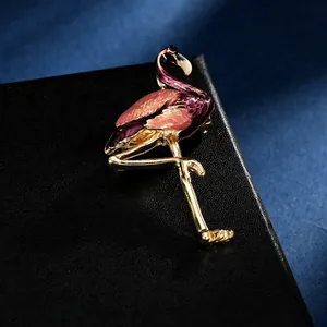Détail macro d'une broche flamant rose et violette avec placage à l'or sur fond noir