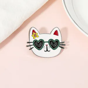 Detail of cartoon cat enamel pin with heart-shaped sunglasses and yellow flower accessory