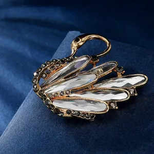 Elegante spilla a cigno placcata in oro con cristalli a goccia su velluto blu scuro