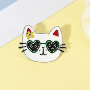 Close-up of cute white cartoon cat enamel pin with heart sunglasses and a yellow flower