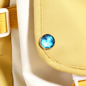Detail of galaxy pattern decorative buckle on yellow and white canvas backpack