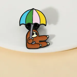 Detailed view of brown enamel sloth brooch holding a vibrant colorful umbrella charm