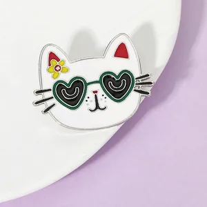 Close-up of white enamel cat brooch with black heart-shaped sunglasses and yellow flower