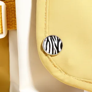 Détail du sac en toile jaune avec boucle décorative zébrée et boucle de sangle blanche