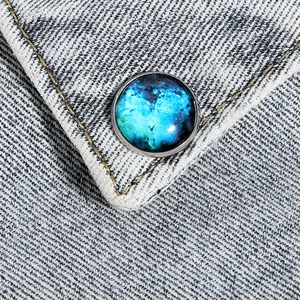 Macro view of a galaxy nebula glass dome brooch on blue denim fabric background