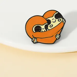 Detailed macro view of heart-shaped brown sloth enamel brooch with polished alloy finish