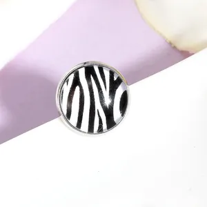 Vue macro d'une broche argentée avec motif zébré noir et blanc et finition brillante