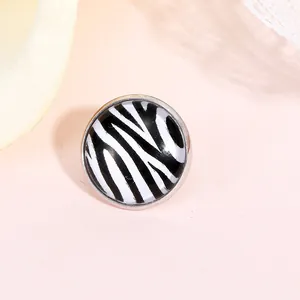 Détail d'une boucle d'oreille en alliage argenté avec motif zébré noir et blanc