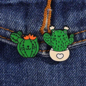Detail of cartoon cat cactus enamel pins pinned on blue denim fabric background