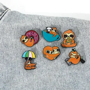 Detailed view of six cute cartoon sloth enamel pins on a casual denim fabric background