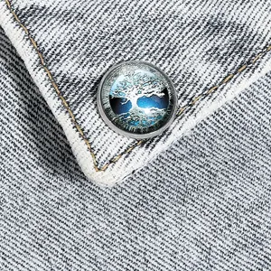 Dettaglio macro della spilla albero della vita in vetro argentato su tessuto denim blu