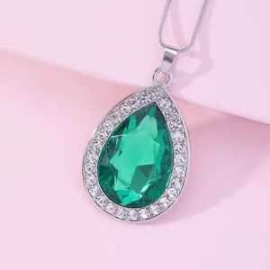 Close-up of teardrop green gemstone pendant with white crystals on a silver snake chain
