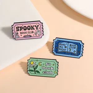 Détail de trois badges en émail en forme de timbres avec motifs Spooky Book Club