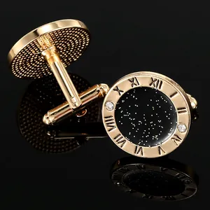 Macro shot of gold cufflinks with black stardust center, Roman numerals and rhinestones