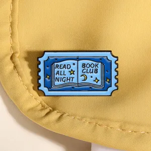 Détail macro du pin's en émail Read All Night Book Club sur un tissu en toile jaune