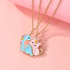 Detail showing magnetic blue dinosaur and pink cat pendants interlocking on gold chains