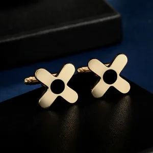 Macro shot of gold-plated X-shaped cufflinks with black enamel on a dark jewelry box