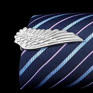 Detail of silver wing tie clip with intricate feather texture on a navy silk tie