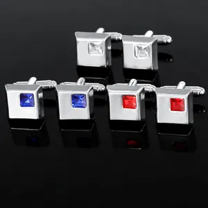 Macro shot of silver square cufflinks with red, blue, and white inlaid crystals