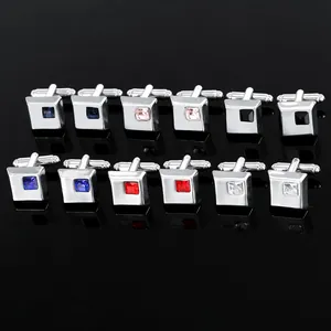 Close-up of square metal cufflinks with multi-colored gemstone inlays in silver mirror finish