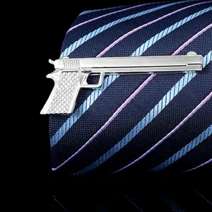 Macro detail of silver pistol-shaped tie clip on navy blue textured necktie fabric