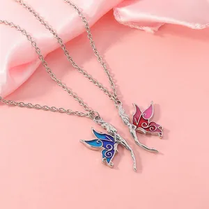Detail of blue and pink enamel butterfly wing necklaces on soft pink silk fabric