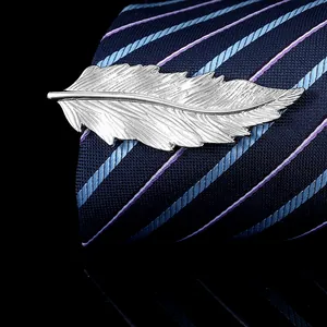 Detailed macro view of a silver feather-shaped tie clip on a dark blue silk tie