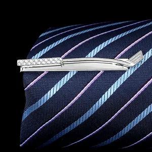 Close-up of a silver golf club tie clip with textured grip on a navy blue striped tie