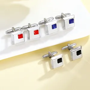 Macro shot of silver square cufflinks set with red, blue, and black inlaid crystals