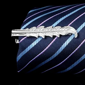 Macro view of silver feather tie clip with detailed metallic texture on a navy tie