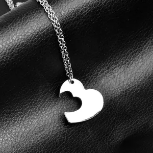 Macro view of minimalist hollow heart pendant necklace on textured black leather surface