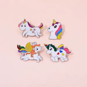 Set of four cute unicorn enamel pins with rainbow details on a soft pink background