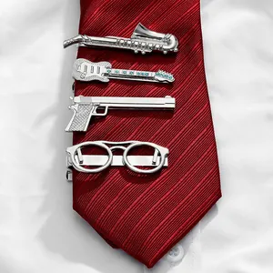Set of 4 silver tie clips with saxophone, guitar, pistol and glasses shapes on red tie