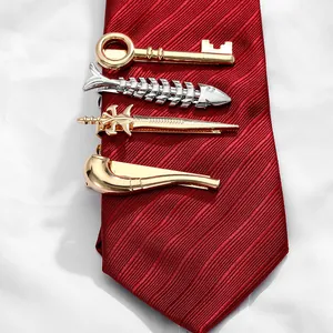 Detailed view of novelty metallic tie clips in key, fishbone, and sword shapes on a red tie
