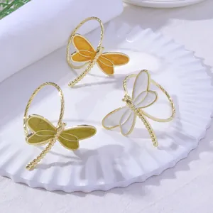 Macro view of gold-plated dragonfly napkin rings with colorful enamel details on wings