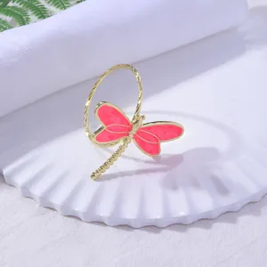 Detailed close-up of golden dragonfly napkin ring with pink wings on white plate