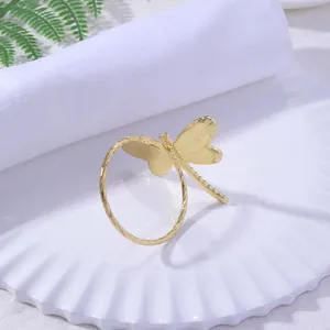 Close-up of golden dragonfly napkin ring with textured wings on a white plate