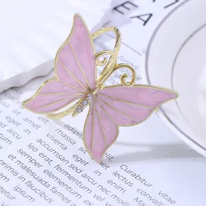 Macro view of golden butterfly napkin ring with pink enamel wings and sparkling rhinestones
