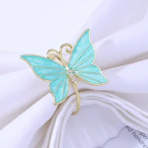 Detailed close-up of a gold butterfly napkin ring with blue enamel wings on a white napkin