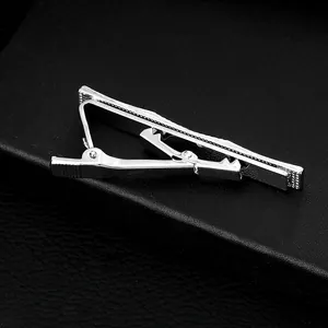 Sleek silver tie clip for men with polished finish and side texture on leather background