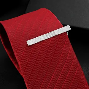Elegant silver tie clip with textured grid pattern on a classic red silk necktie