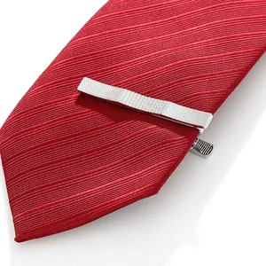 Detail view of silver tie clip with textured grid pattern on a red diagonal tie