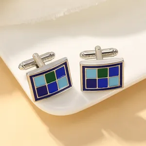 Detailopname van rechthoekige zilveren manchetknopen met blauw en groen emaille rasterpatroon