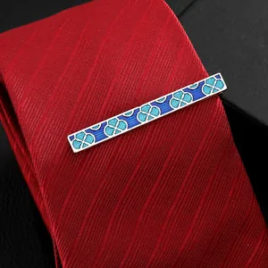 Men's silver tie clip with blue enamel patterns on a red textured necktie
