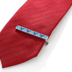 Detail of silver tie clip with blue enamel patterns on a red silk necktie