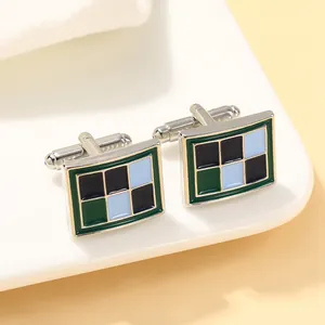 Macro-opname van zilveren rechthoekige manchetknoppen met groen en blauw ruitpatroon