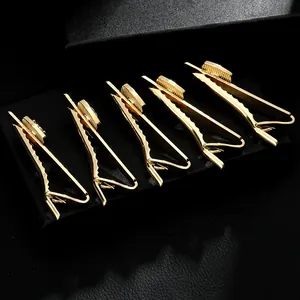 Detalle macro de 5 pasadores de corbata dorados con base redonda sobre fondo de cuero negro