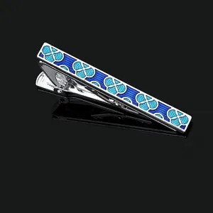 Macro shot of silver tie clip with blue geometric enamel patterns on black background